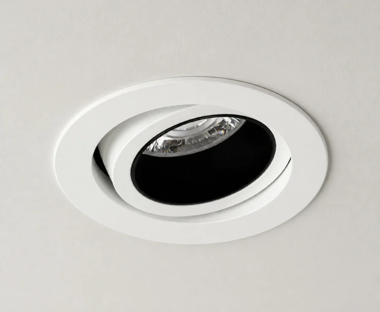 Prism tilting recessed downlight installed in a ceiling with its black baffle visible
